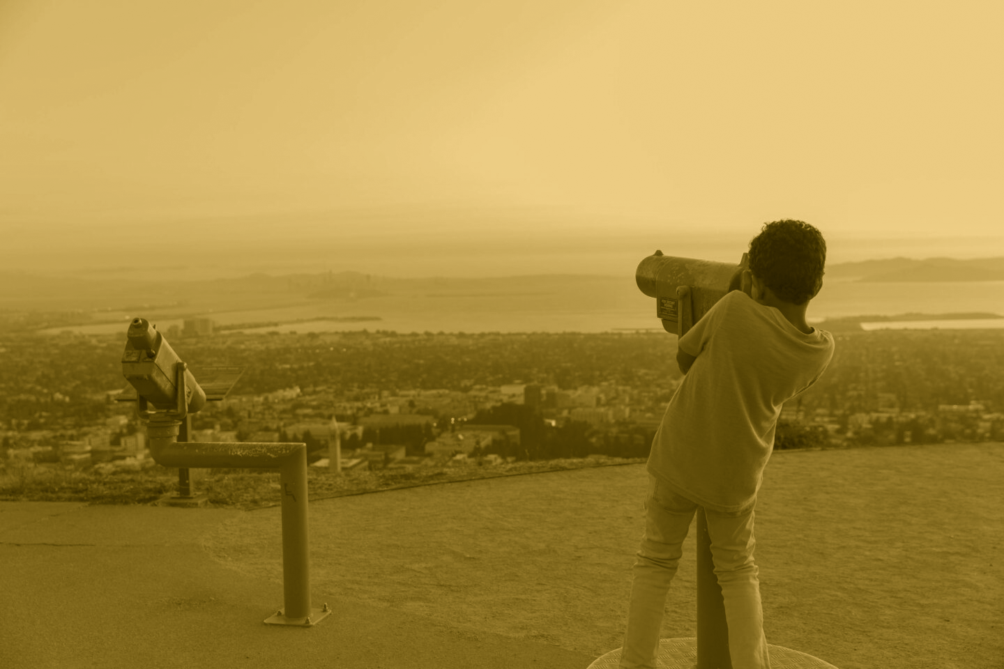 A young person looks through a telescope of the view at The Lawrence.
