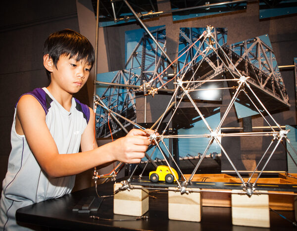 A young person is building a model bridge