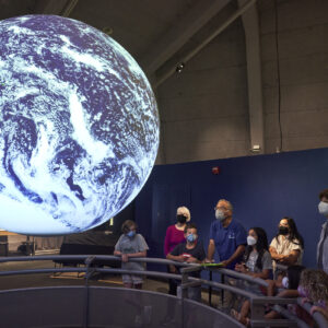 A group of visitors observing the globe projected on Science On A Sphere