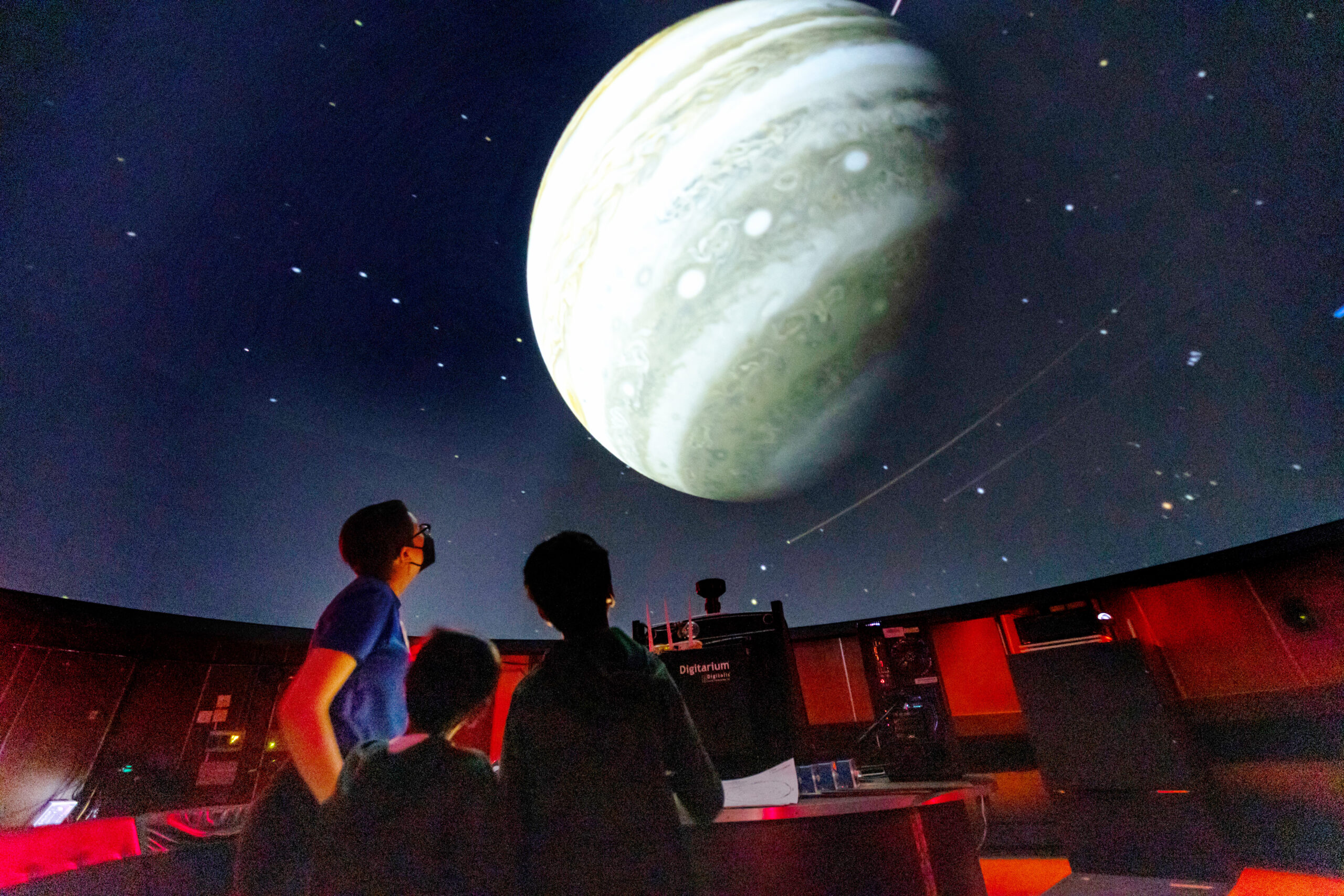 Inside view of the Planetarium with Lawrence staff and visitors. A large planet is shown on the dome.