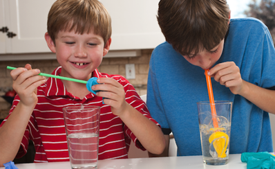 Two children with straws and glasses they are using to illustrate a heart valve