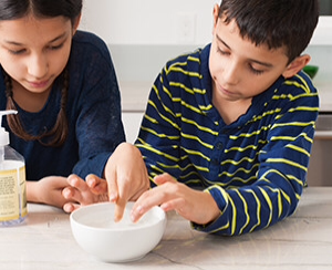 Two young people examining a bowl of water while learning about water bugs