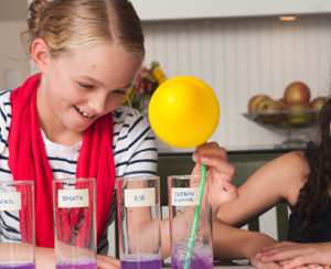 A young person holds a balloon in a science experiment about what's in your breath
