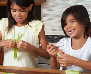 Two children holding celery that they are using for their science experiment about bone fractures