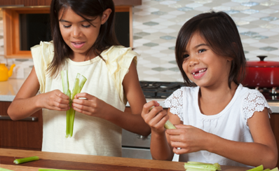 Two children holding celery that they are using for their science experiment about bone fractures