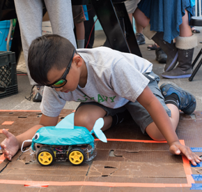 A young person testing a constructed robot car