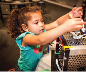 A child examining a scientific machine with gears