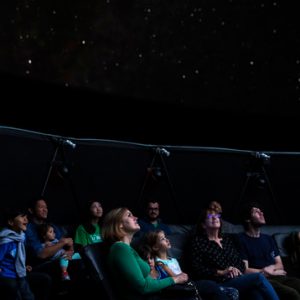 A group of people sitting in the planetarium and looking up at the stars