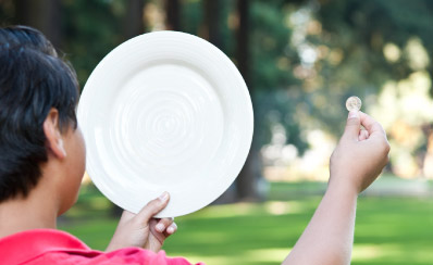 A child holding up a plate and a coin