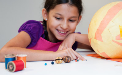 A young person is making a model of the sun and the earth.