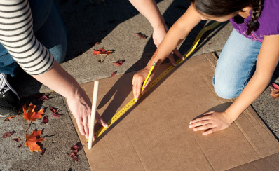 A view of two sets of hands as they draw a line using a tape measure