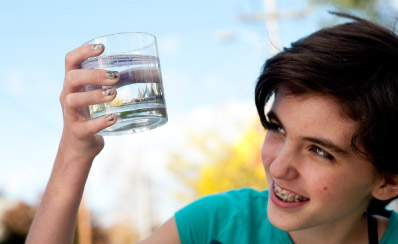 A young person holding up a glass of water