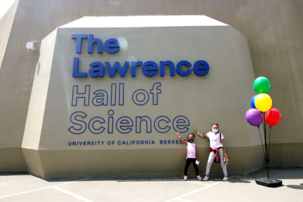 Two children standing at The Lawrence Hall of Science sign on the plaza