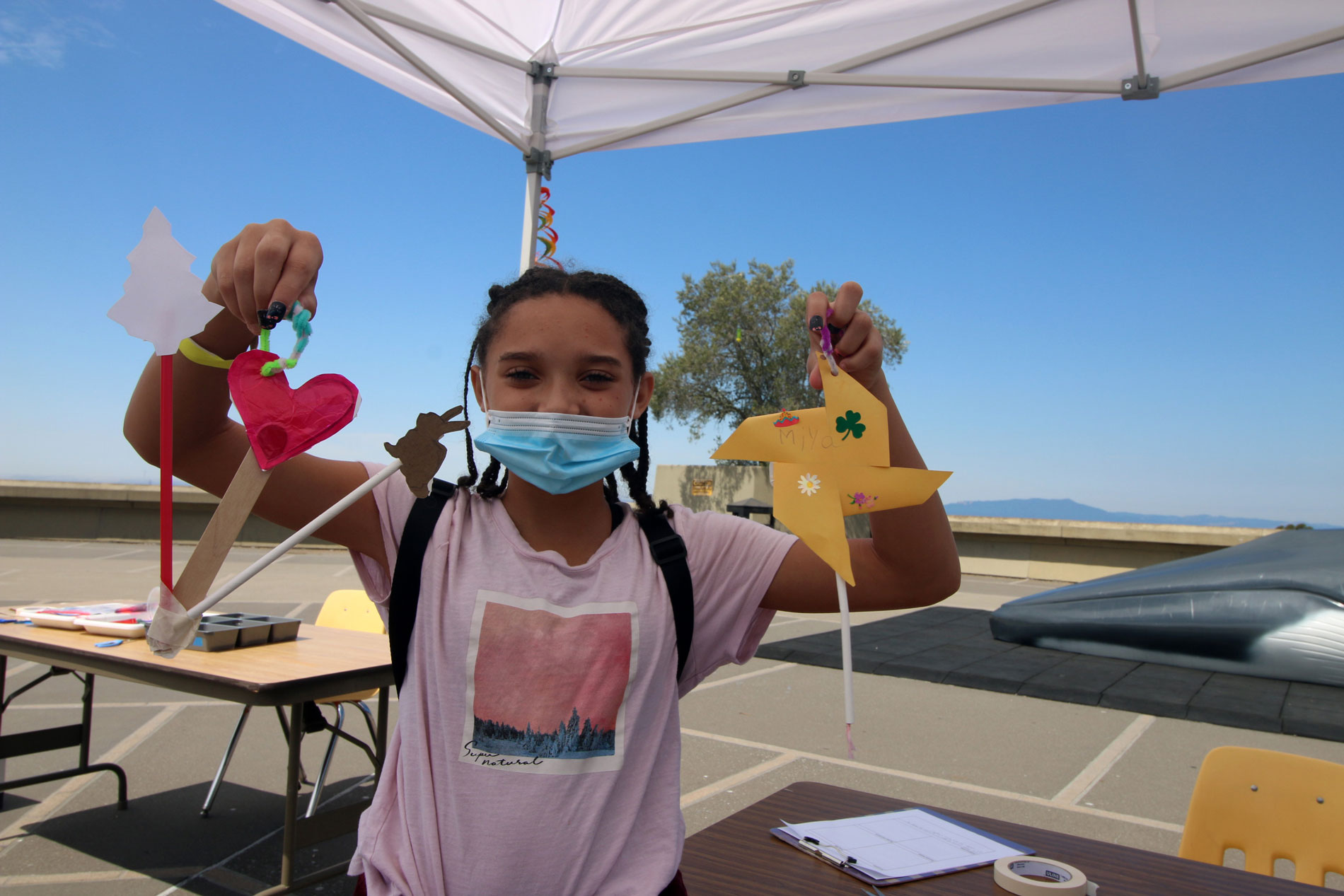 A young person holding up her paper sculptures she made during Summer Fundays