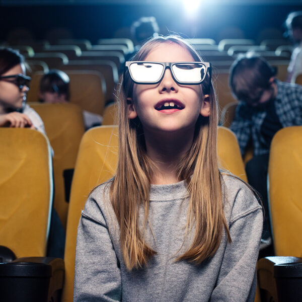 A girl wearing 3D glasses watching a movie in a theater