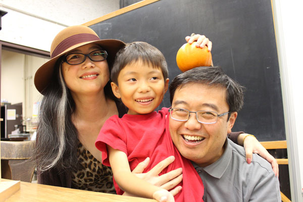 A family smiling together and the child is holding a pumpkin