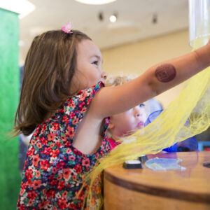 A young girl putting lightweight fabric into an air tube