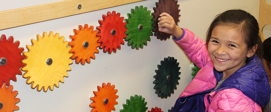 A young person turning gears on an exhibit