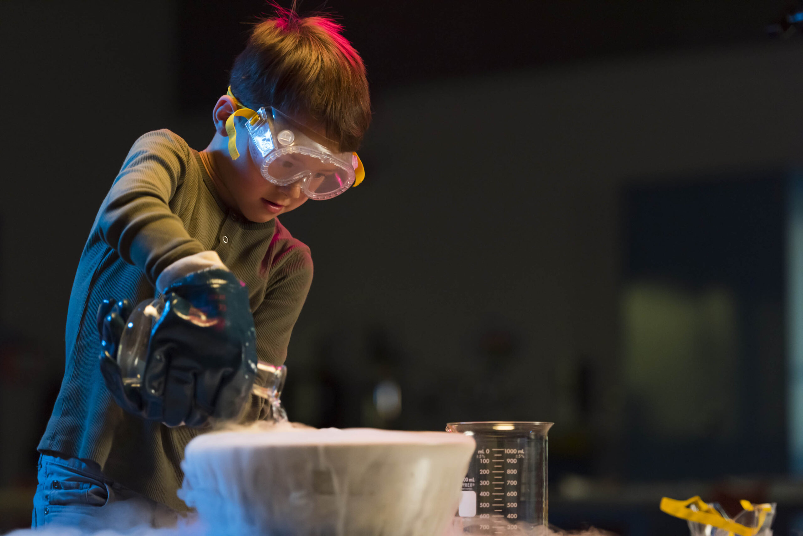 A child is wearing safety glasses and pouring dry ice