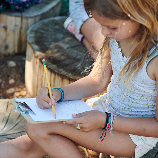 A visitor records her observations with pencil and paper in the Outdoor Nature Lab