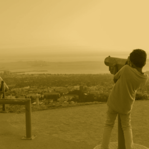 A child looks through a telescope at the view