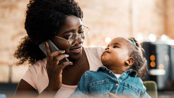 A woman looks at her child while talking on the phone