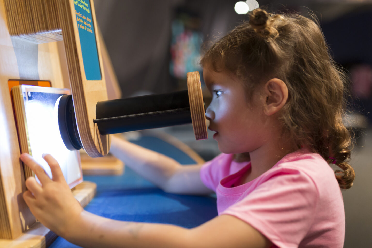 A young child is looking through a tube at a science exhibit
