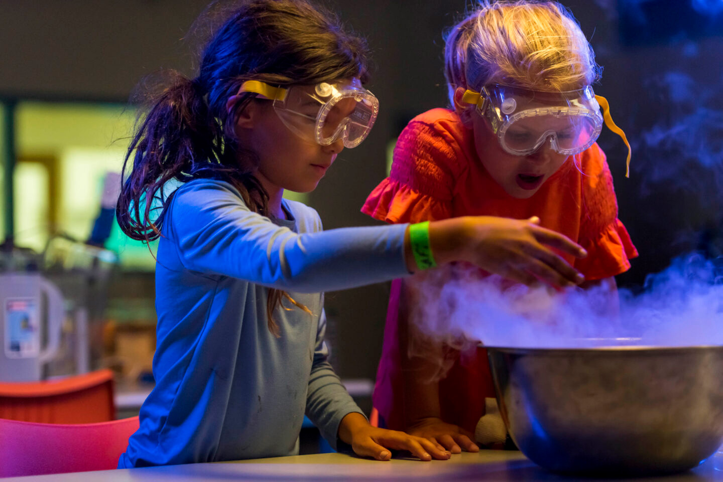 Two young people wearing safety goggles conducting a science experiment.