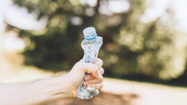 A hand is squeezing a plastic water bottle