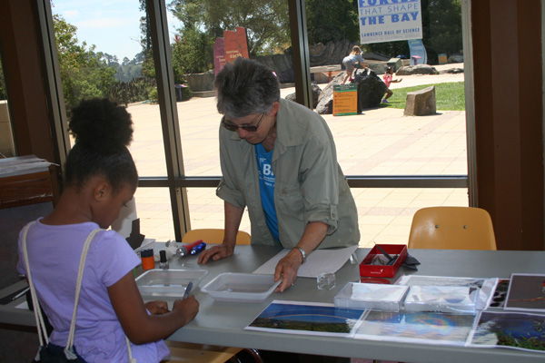 A child is making an iridescent bookmark at an event