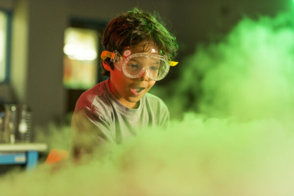 a boy looks in wonder at a cloud of vapor produced by dry ice