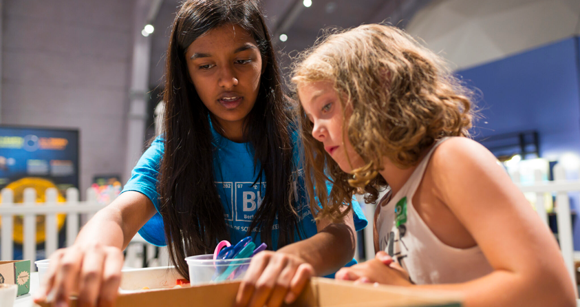 A volunteer and a child work together on a science project.