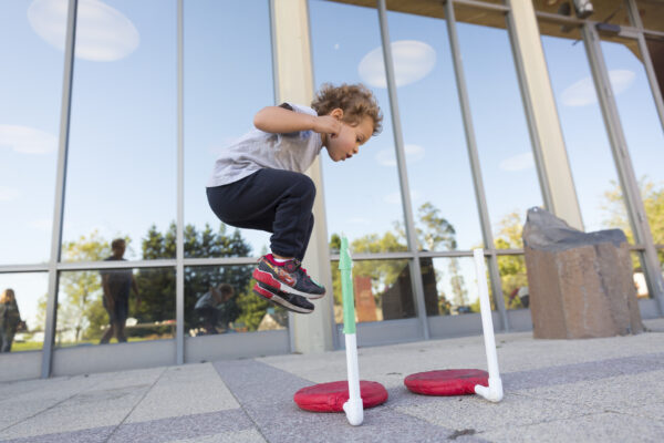 A boy in mid air jumping onto a stomp rocket launcher