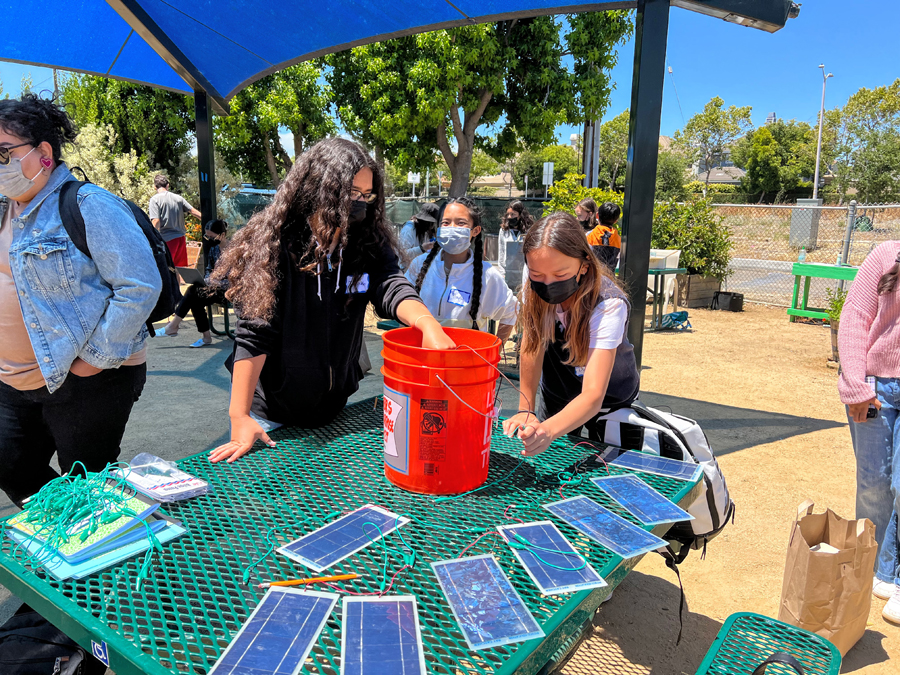 Students are outdoors at a table working on a solar project at Solar Camp.