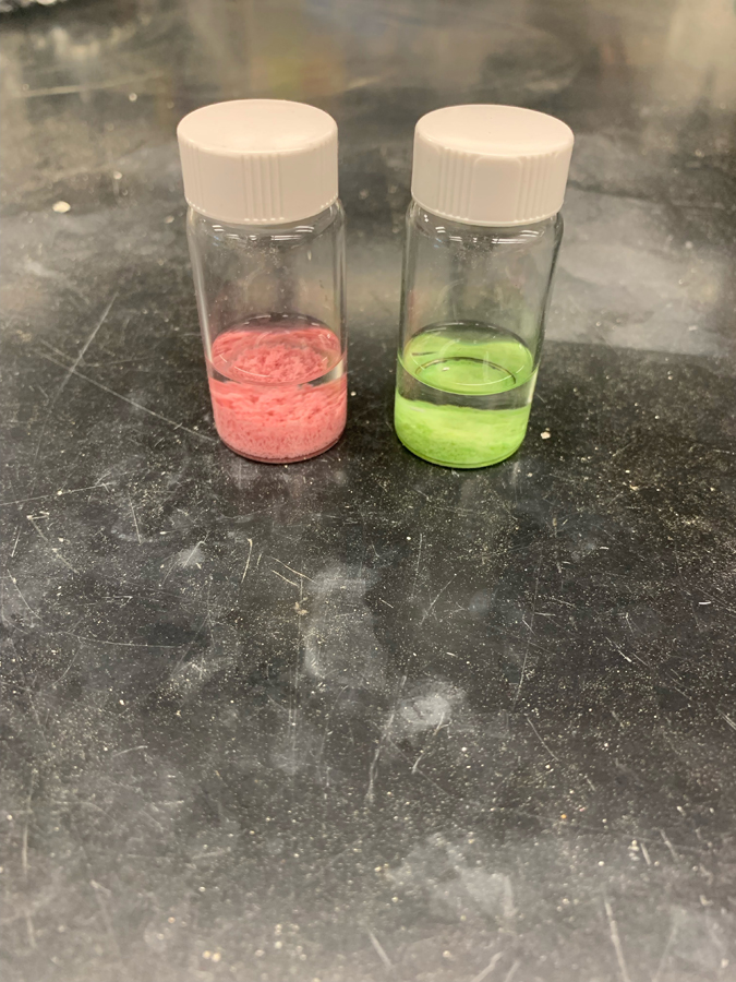 Two small bottles, one with pink contents and one with light green contents