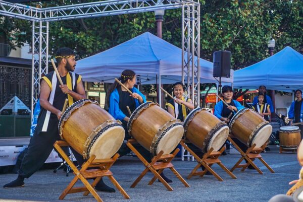 A group of performers from Cal Taiko band drumming on stage