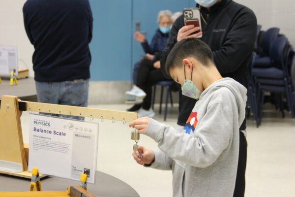 A boy testing out different weights on a balance scale