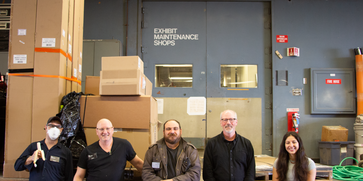 Four men and one woman, the Production Studio team at The Lawrence, stand in front of the entrance to the exhibit shop.