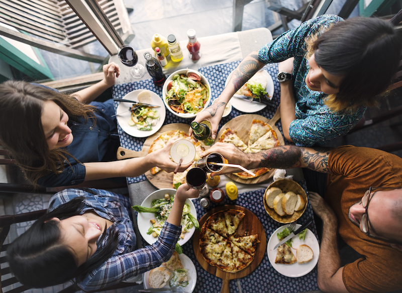 Four people are eating together and sharing a meal of various dishes