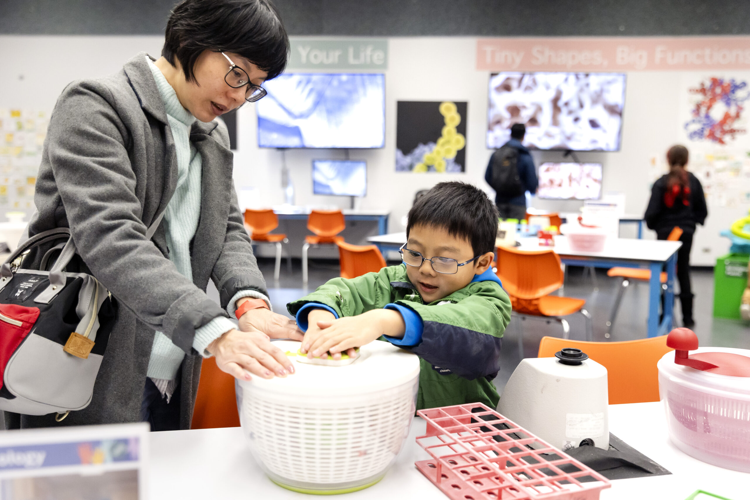 An adult and a child engaging with a hands-on biotech science activity.