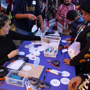 Children and adults working on craft activity at Dia de los Muertos event