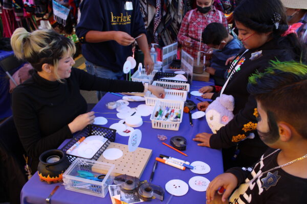 Children and adults working on craft activity at Dia de los Muertos event