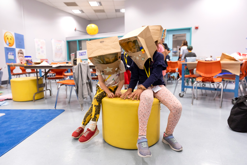 Two students are wearing their astronaut helmet creations they made during a camp activity