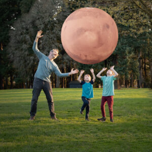 A man and two kids outside looking at an augmented reality planet