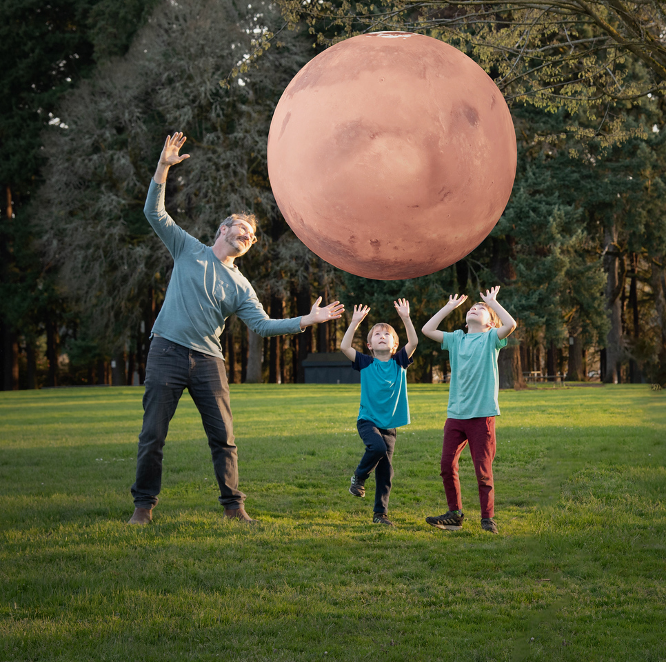 A man and two kids outside looking at an augmented reality planet