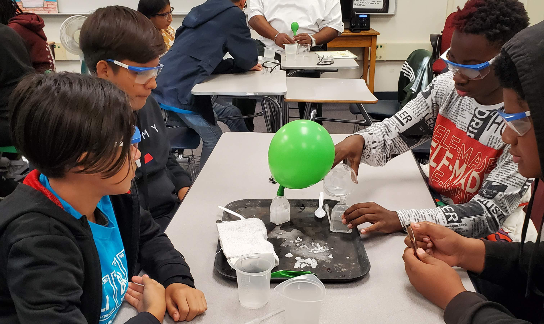 Students are around a table participating in a science experiment with dry ice.