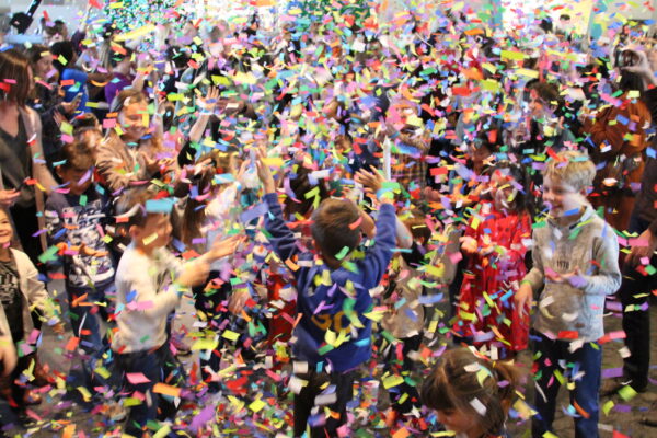 Kids and families marvel at large amount of confetti falling from above