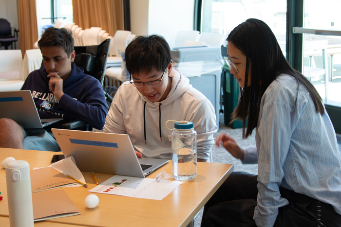 Two students use a computer while working together on AI small group work.