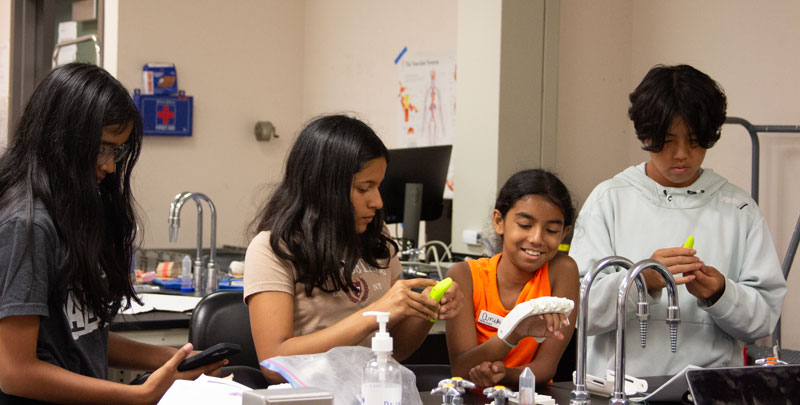 Four teens work together during mechanical hand construction during the Body Systems Teen Research Program