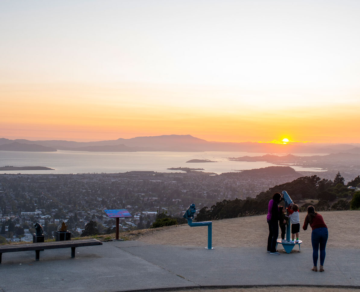 Sunset at The Lawrence. Visitors look through telescopes at the view of the bay.
